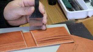 Artisan personnalisant un porte-cartes de voyage en maroquinerie personnalisée