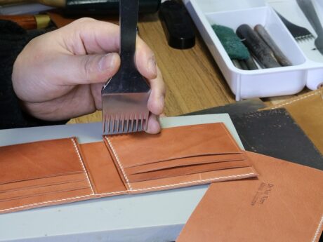 Artisan personnalisant un porte-cartes de voyage en maroquinerie personnalisée