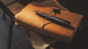 Carnet de voyage fermé avec un stylo posé dessus, prêt à accueillir des notes et dessins de voyage.